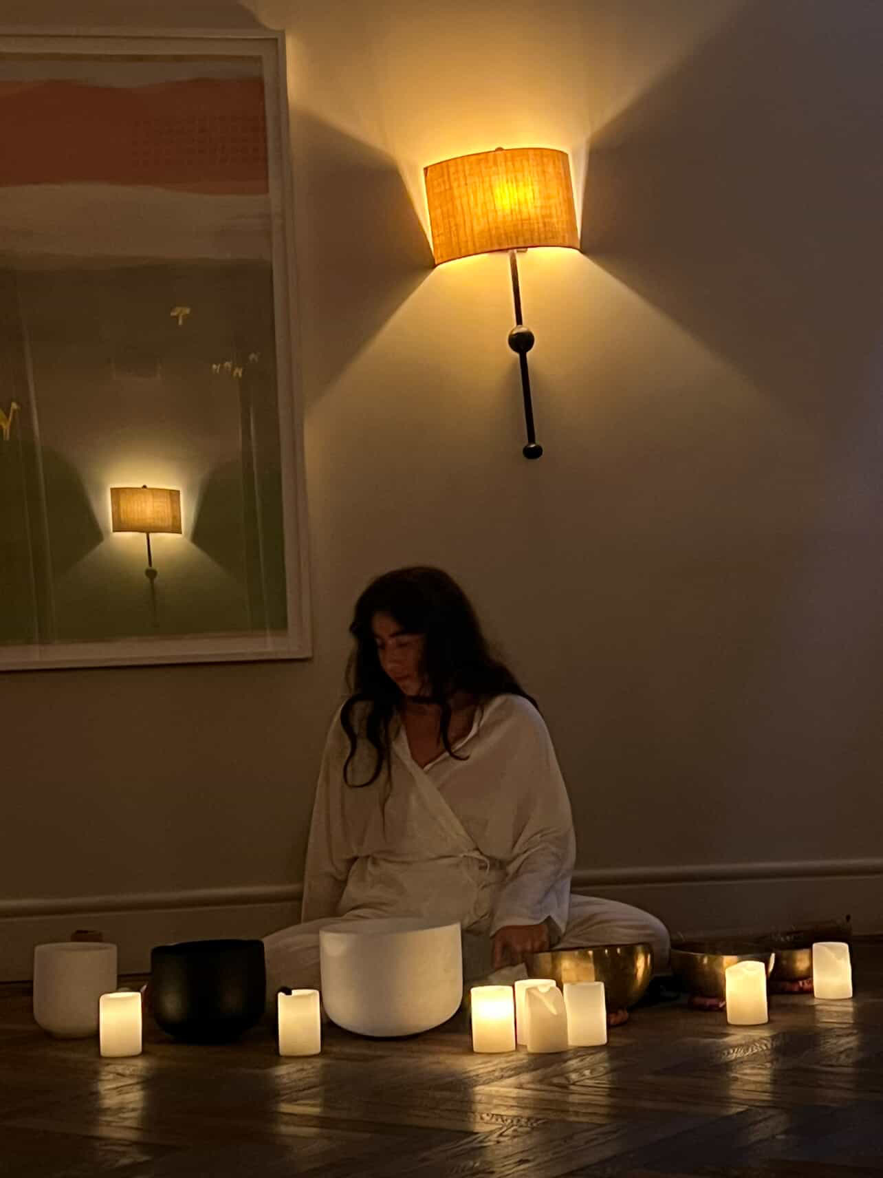 Seated with singing bowls beneath warm light.